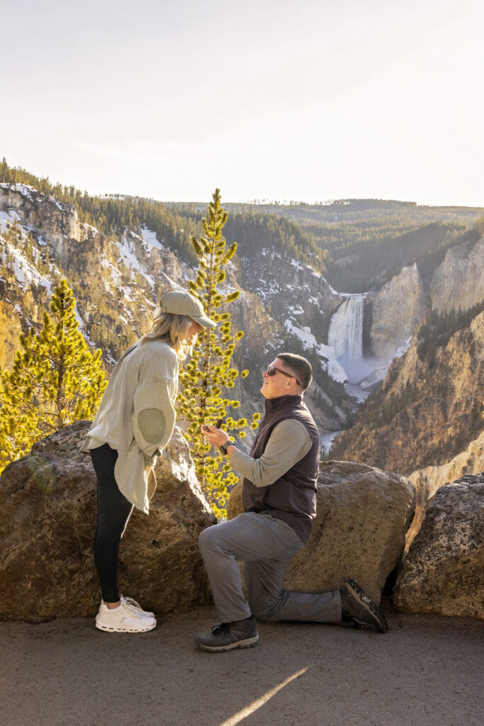 Romantic engagement photo in Yellowstone with vibrant sky and canyon setting.
