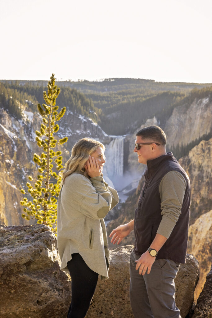 Warm sunset glow on the couple as they pose with canyon overlook behind them.