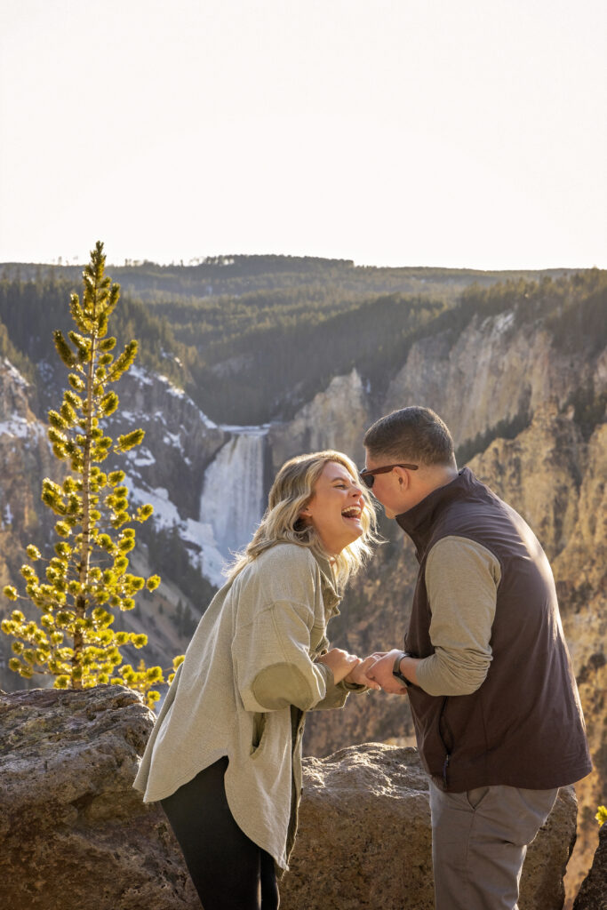 Ashlyn holding Kasey’s hand with the canyon and falls glowing behind them.
