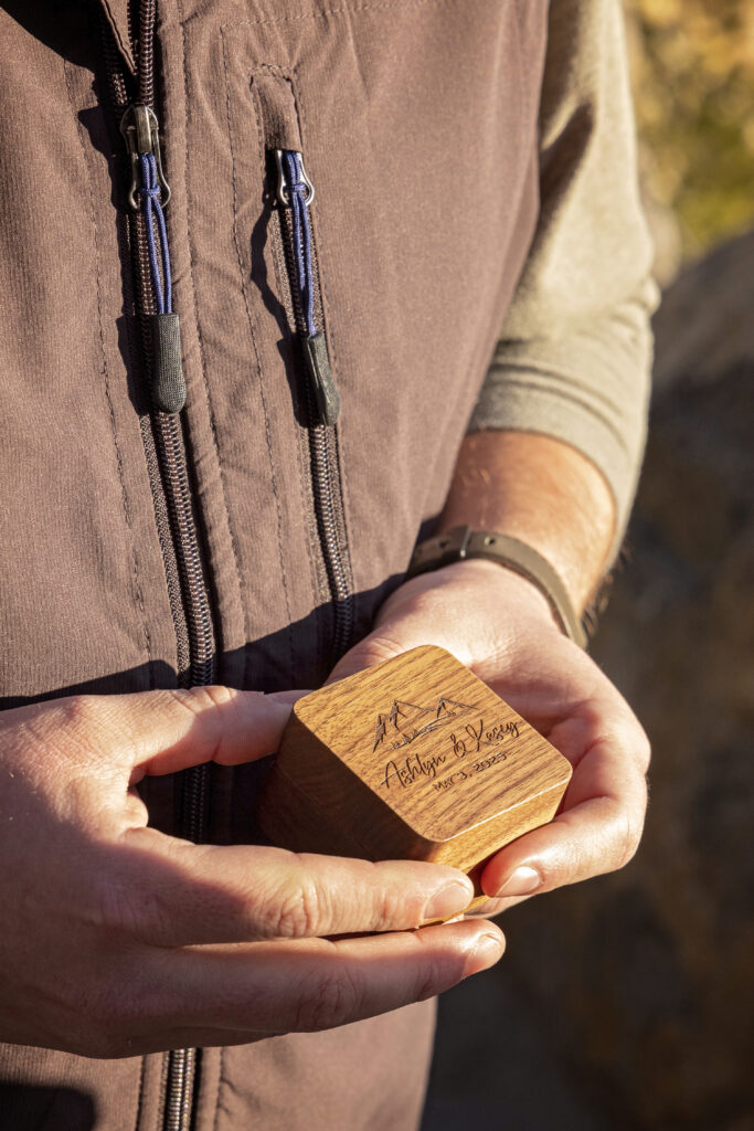 Artistic detail shot of the engraved engagement box resting in Kasey's hands.