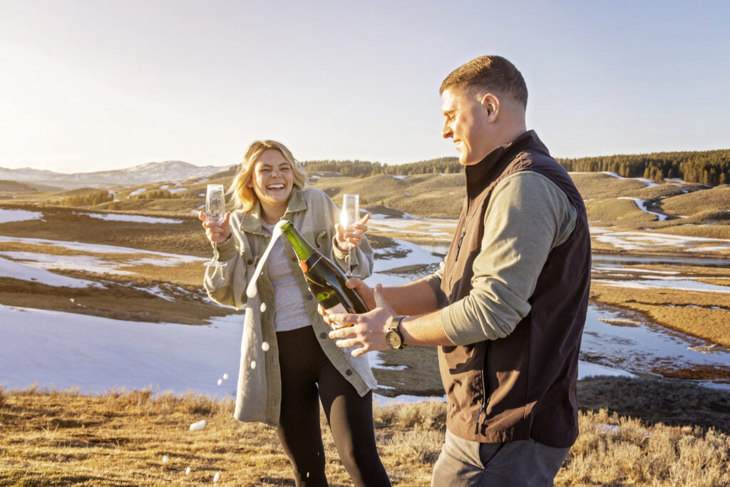 Joyful moment of couple spraying champagne after engagement at Artist Point during golden hour.