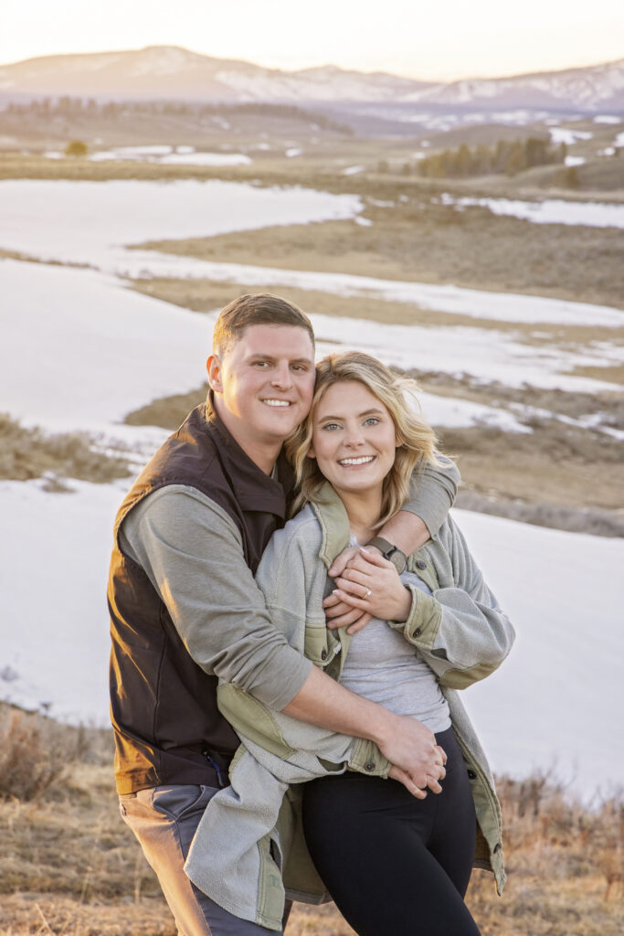 Candid engagement photo of Ashlyn leaning into Kasey at sunset in Yellowstone.