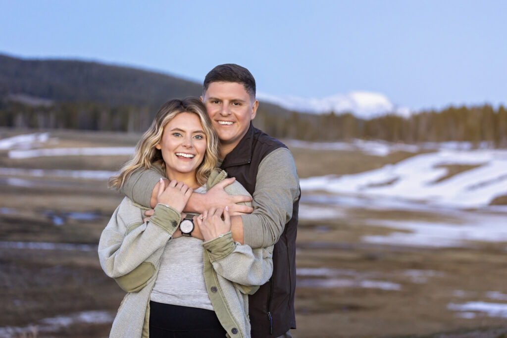 Romantic portrait of couple at Yellowstone with blue mountain hues behind them.