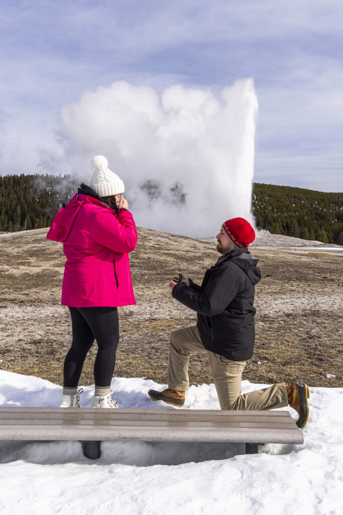 Keith and Jill standing together as Old Faithful begins to erupt in the background.