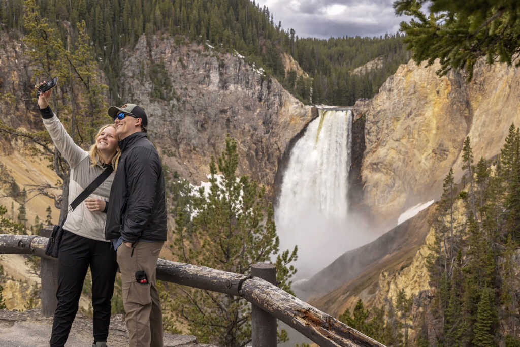 Couple standing at overlook with Yellowstone Falls in the distance