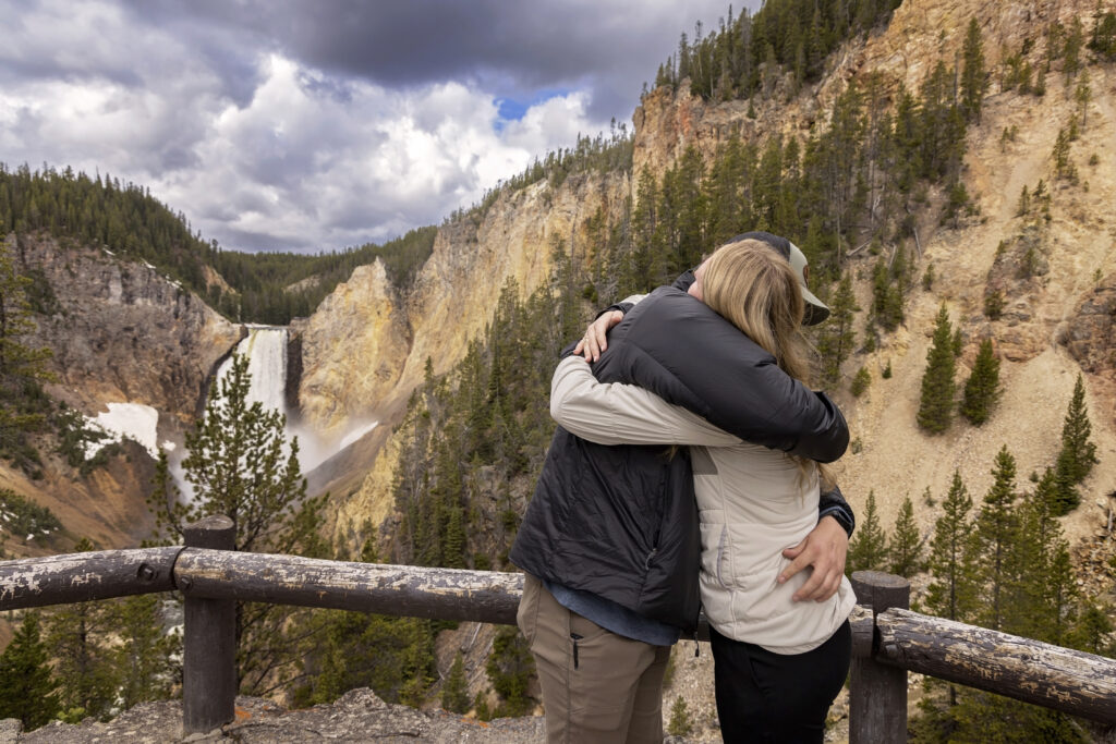 Newly engaged couple hugging in front of Yellowstone Falls