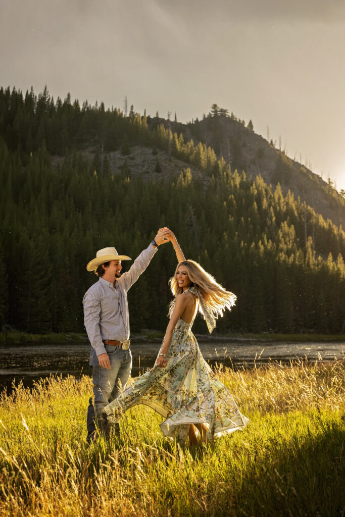Newly engaged couple dancing at sunset during their Yellowstone engagement session by the river