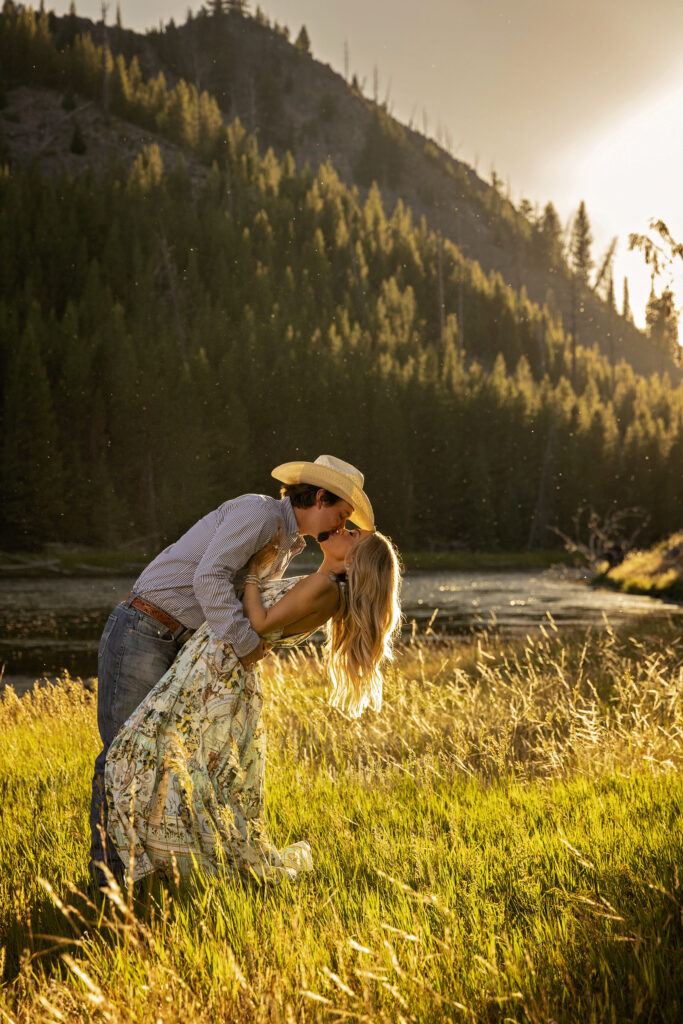 Man dipping and kissing his fiancée at sunset after a Yellowstone proposal along the Madison River