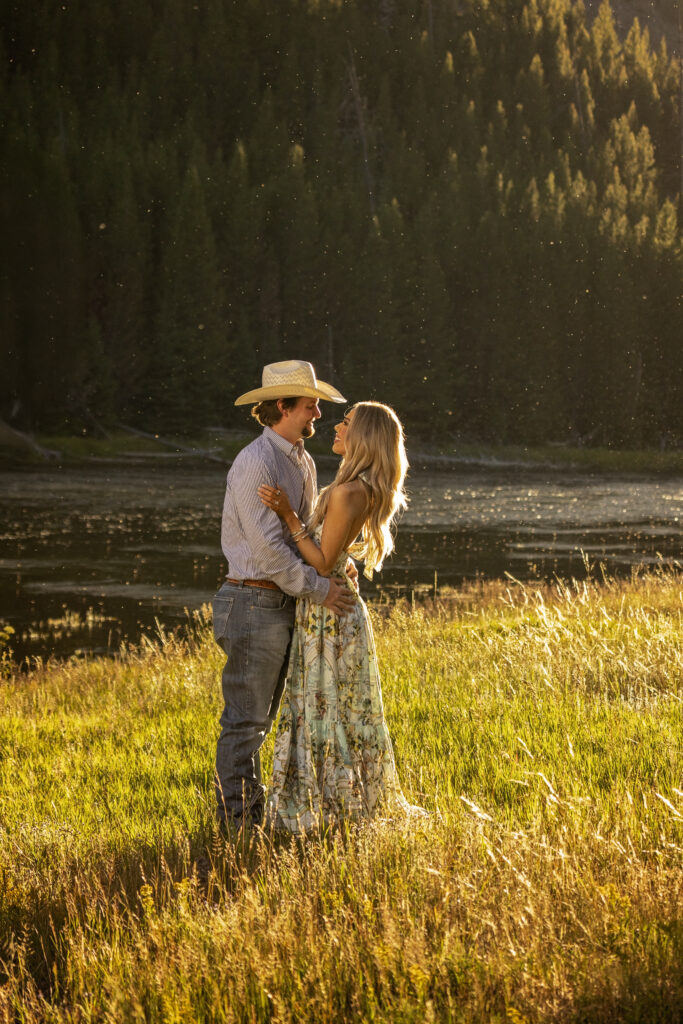 Couple smiling at each other at sunset after their Yellowstone surprise proposal on the Madison River